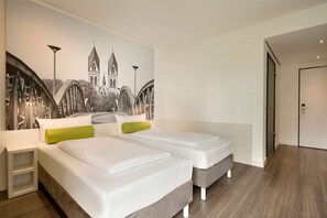 A hotel room with two beds, a mural of a bridge, and a door to the right. - Freiburg (Freiburg im Breisgau)