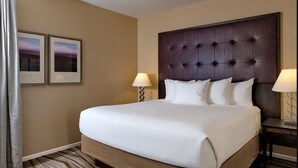 Ett hotellrum med en stor säng, två sänglampor, en sänggavel och två inramade tavlor på väggen.