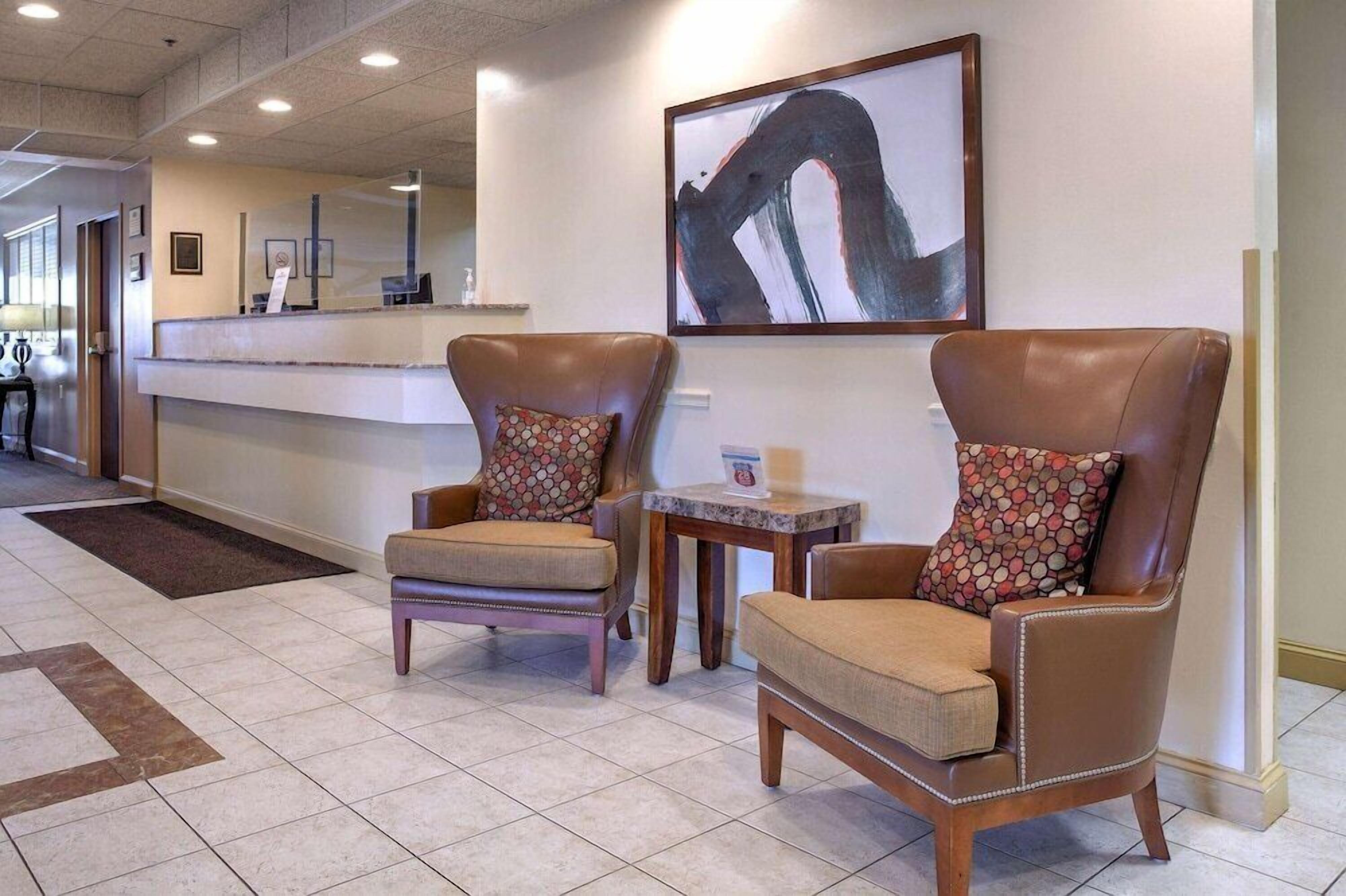 A lobby with two leather armchairs, a reception desk, and a large abstract painting.