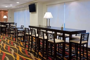 Un salón de conferencias con una larga mesa, sillas, un televisor y una alfombra estampada.