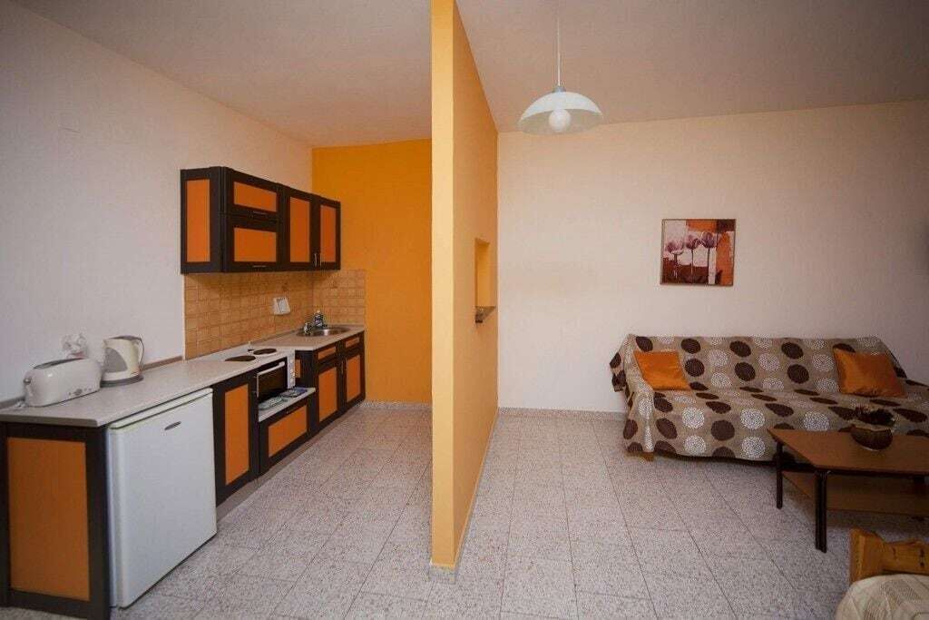 A compact living space with a kitchenette, a sofa, and a dining table.