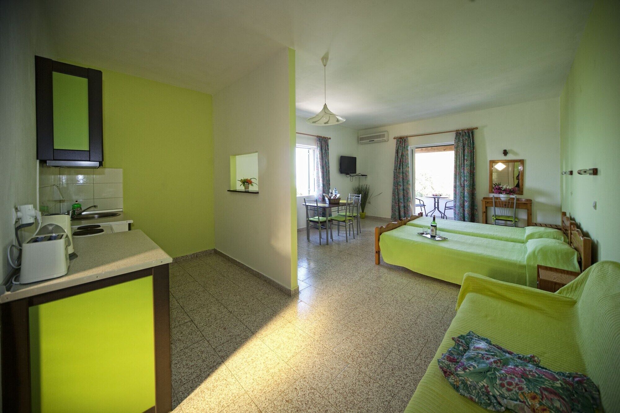 A room with a kitchenette, a dining area, and a bed.