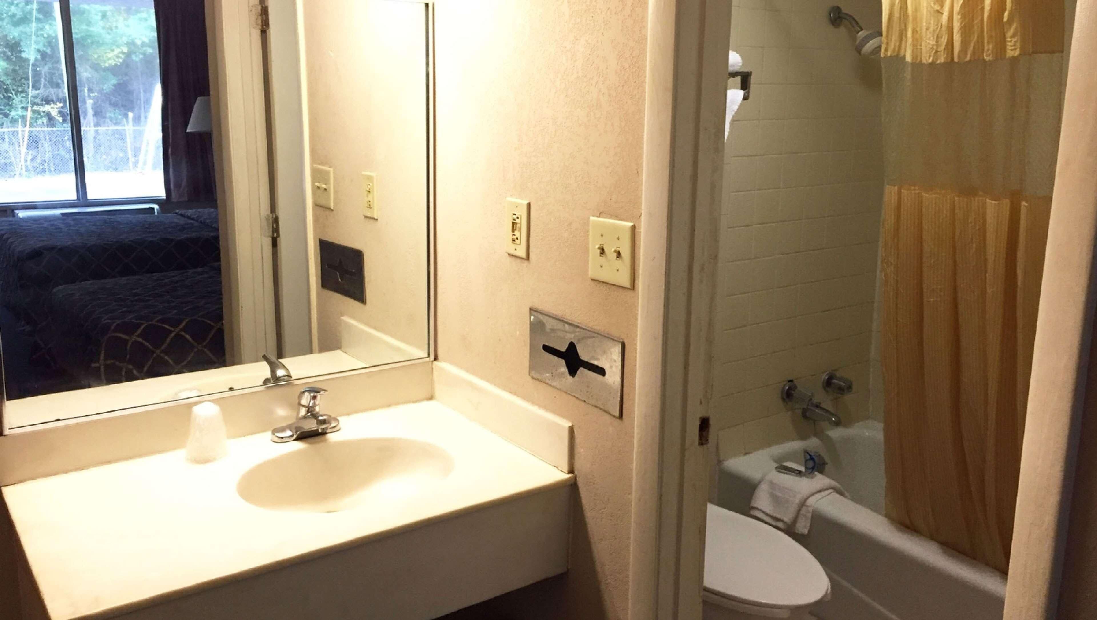 A bathroom with a sink, mirror, toilet, and shower.