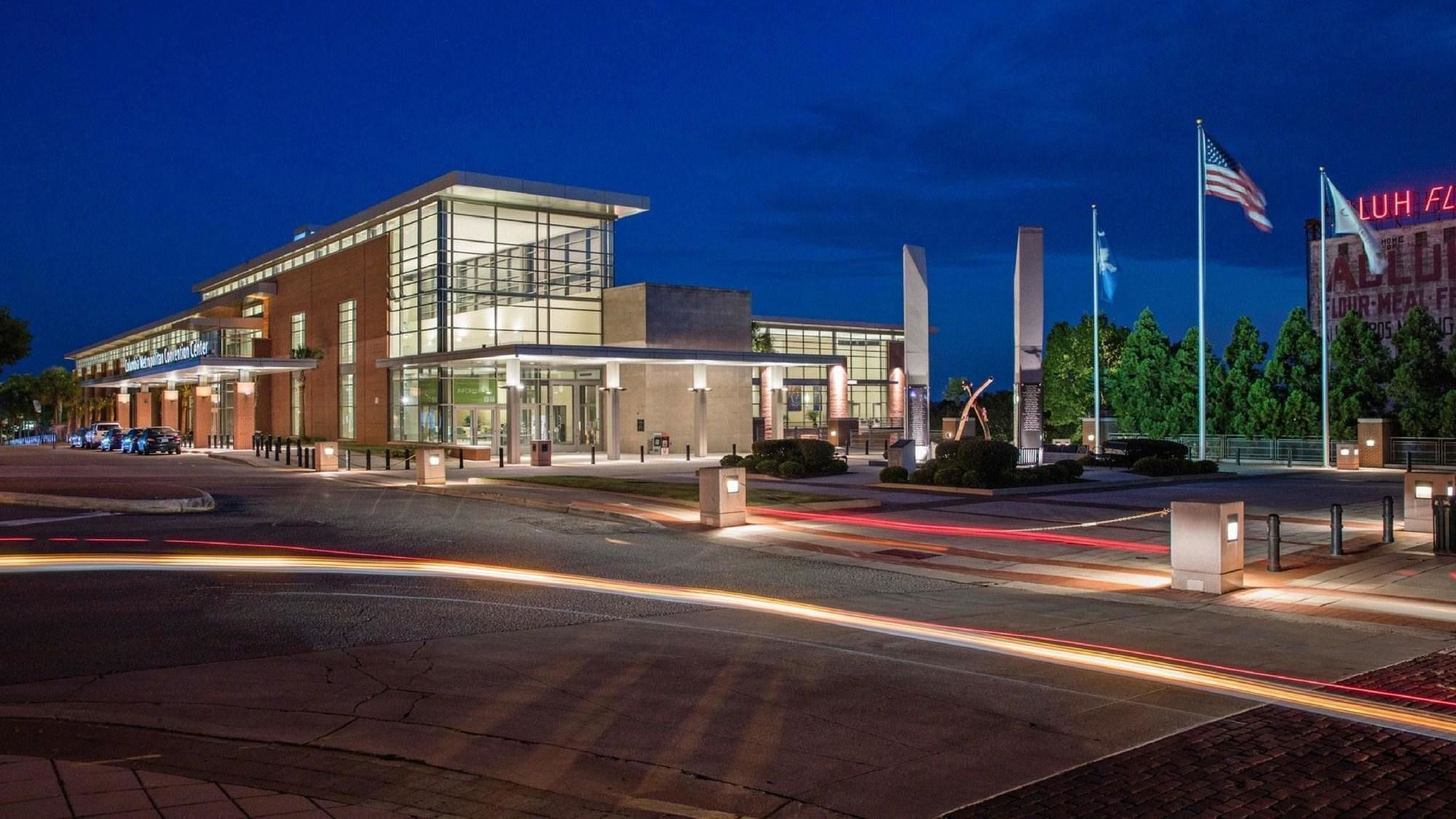 A modern building with a glass facade, a covered entrance, and multiple flagpoles.
