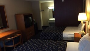 A hotel room with a bed, a desk, a television, a mirror, and a bathroom. - Magnuson Hotel Columbia (Columbia)