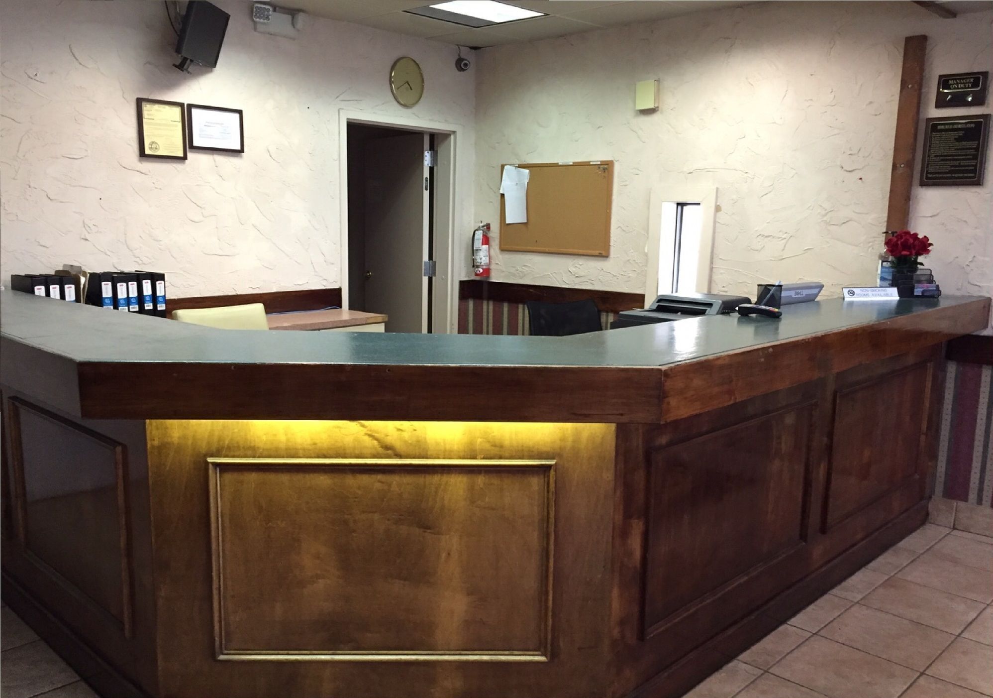 A reception desk with a wooden counter, a clock, framed certificates, and a bulletin board.