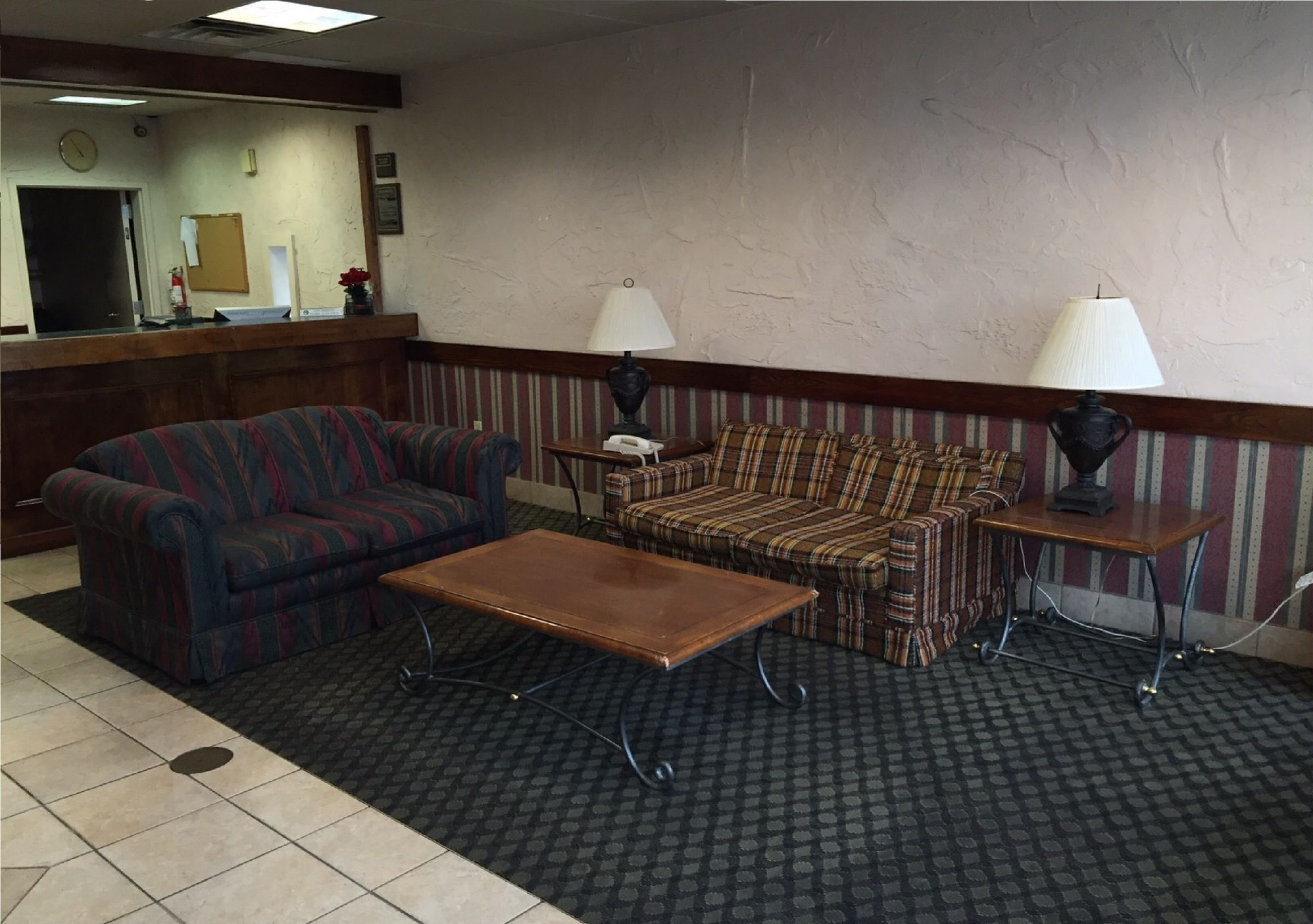 A lobby with two sofas, a coffee table, lamps, a reception desk, and a clock.