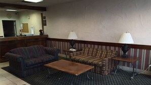 A lobby with two sofas, a coffee table, lamps, a reception desk, and a clock. - Magnuson Hotel Columbia (Columbia)