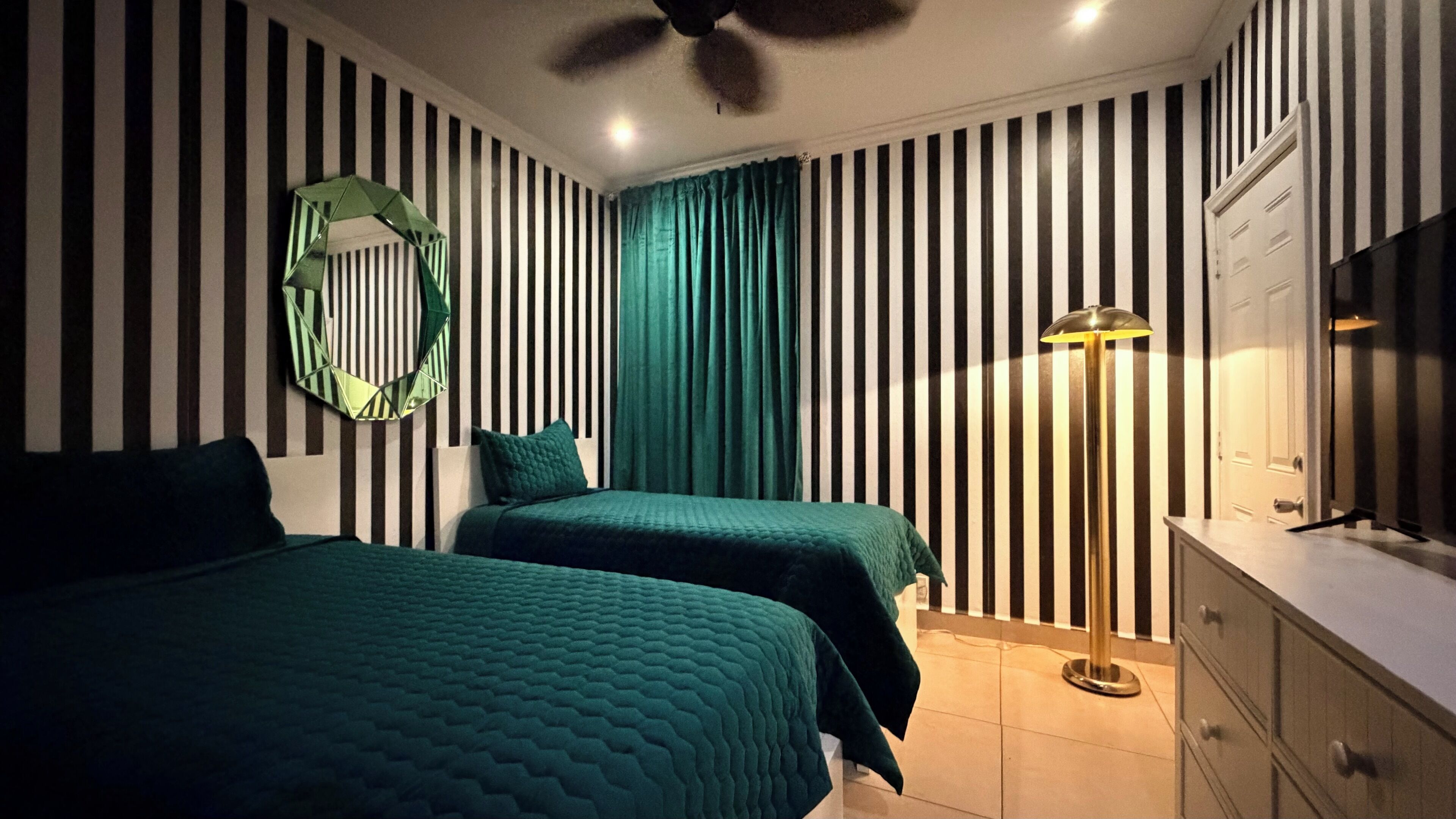 Una habitación con dos camas, un espejo, una lámpara y un aparador.