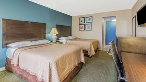 A hotel room with two beds, a desk, a chair, a TV, and a door leading to another room. - Travelodge by Wyndham Virginia Beach (Virginia Beach)