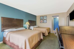 A hotel room with two beds, a desk, a chair, a TV, and a door leading to another room. - Travelodge by Wyndham Virginia Beach (Virginia Beach)