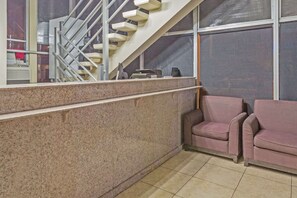 A corner of a hotel lobby with a marble wall, a staircase, and two upholstered chairs. - Travelodge by Wyndham Virginia Beach (Virginia Beach)