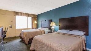 A hotel room with two beds, a desk, a chair, a TV, and a window with curtains. - Travelodge by Wyndham Virginia Beach (Virginia Beach)