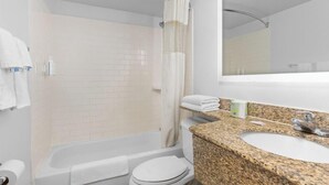 A bathroom with a bathtub, toilet, sink, and shower curtain. - Travelodge by Wyndham Virginia Beach (Virginia Beach)