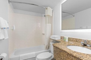 A bathroom with a bathtub, toilet, sink, and shower curtain. - Travelodge by Wyndham Virginia Beach (Virginia Beach)