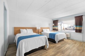 A hotel room with two beds, a window with curtains, a hanging coat rack, and a view of the street outside. - Travelodge by Wyndham Virginia Beach (Virginia Beach)