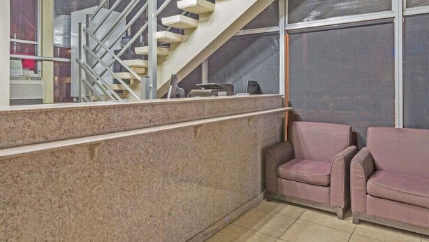 Eine Lobby mit Treppe, einer Rezeption und zwei Sitzbereichen.