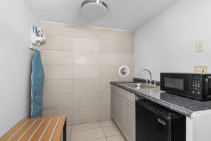 Cozinha compacta com micro-ondas, pia e uma pequena mesa.