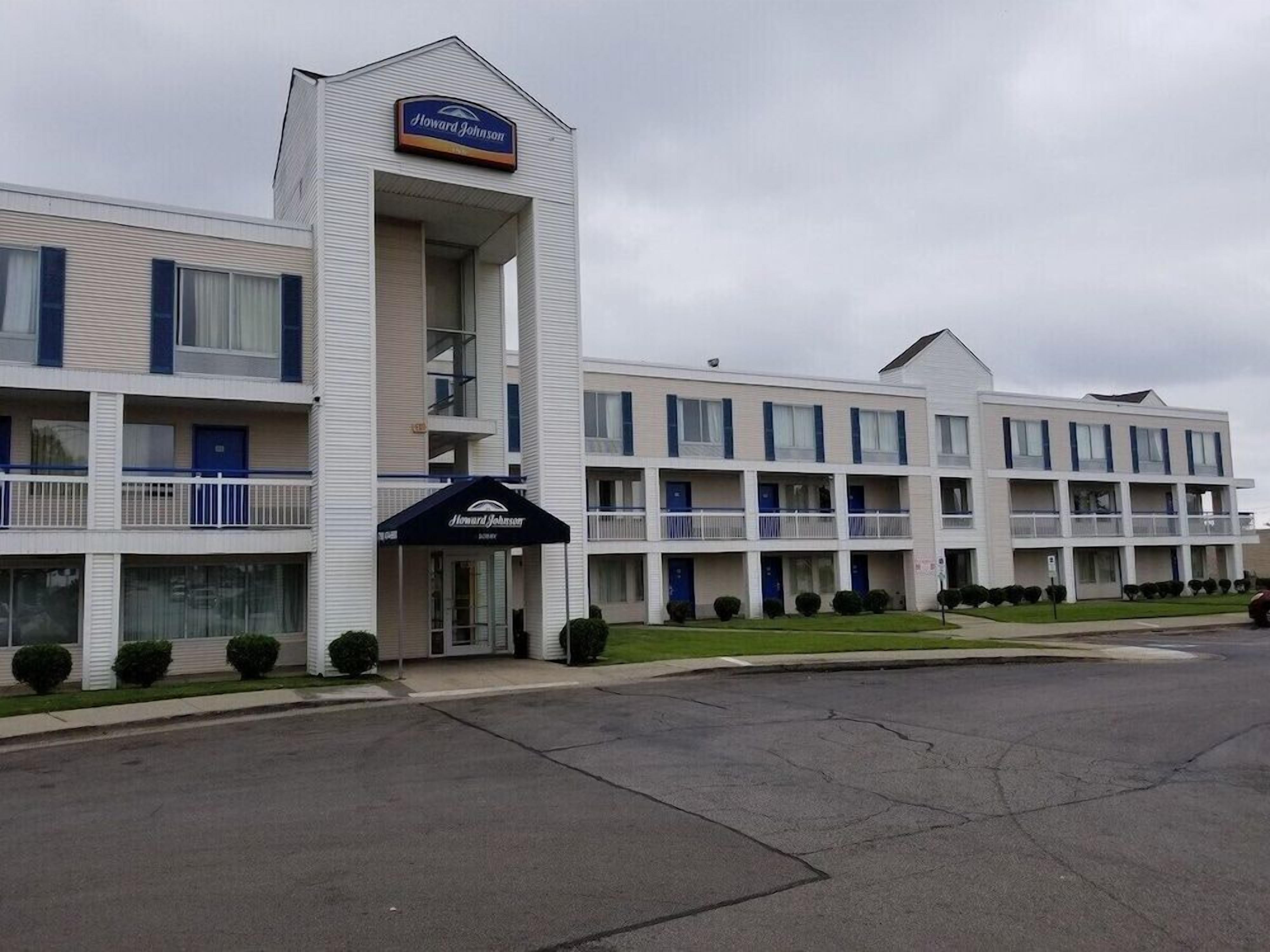 Un hotel Howard Johnson con una estructura de dos pisos, una entrada central y un estacionamiento.