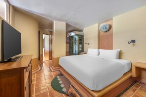 Ein Hotelzimmer mit einem großen Bett, einem Flachbildfernseher, einer Holzkommode und einem Fliesenboden.
