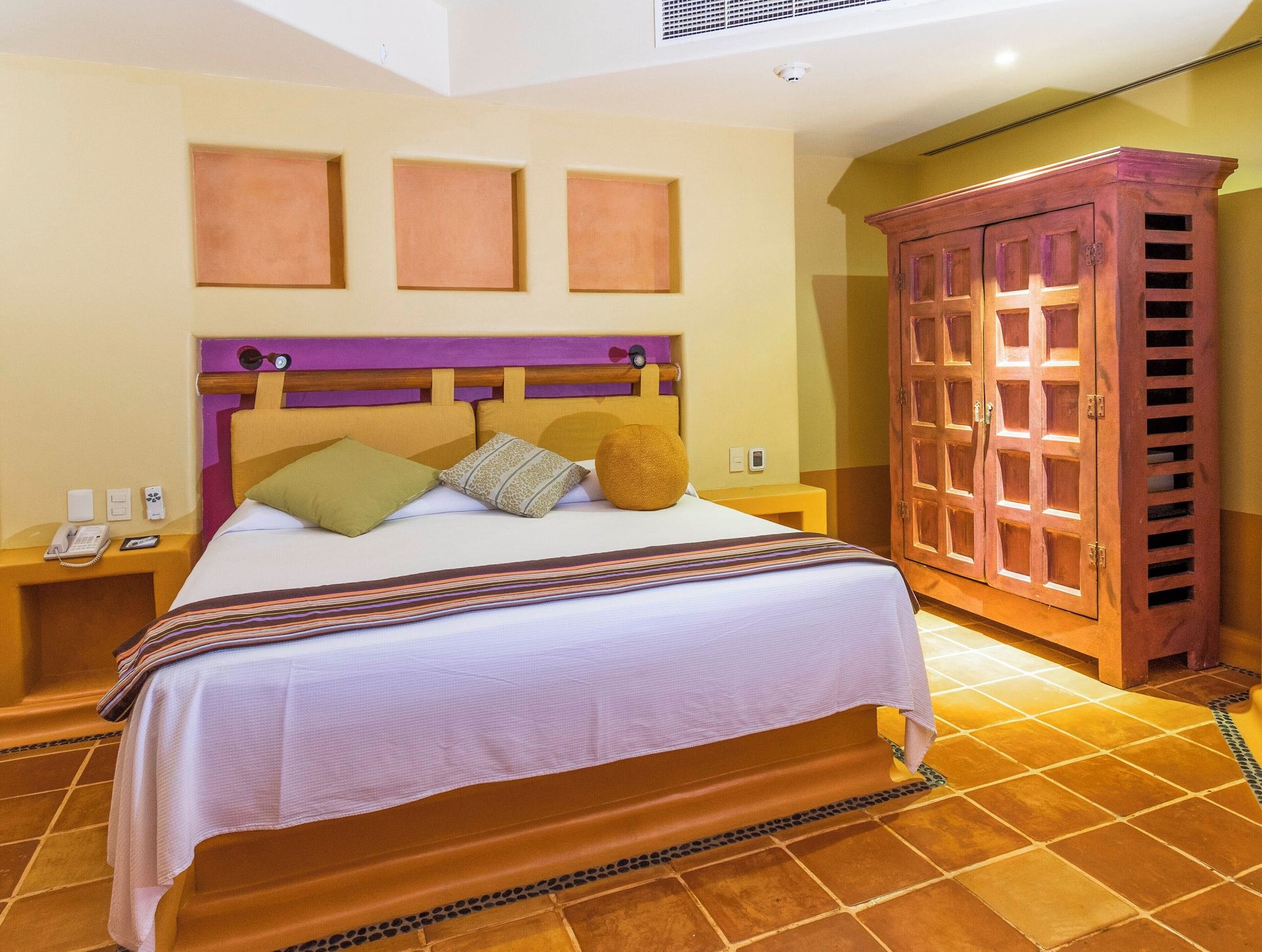 A hotel room with a bed, nightstands, a telephone, and a wardrobe.