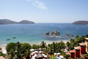Un resort costero con playa, palmeras y vistas al mar.