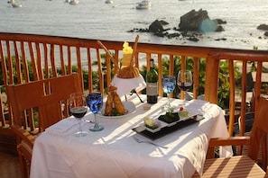 A table set with a bottle of wine, glasses, a plate of food, and a decorative glass.