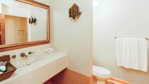 A bathroom with a large mirror, a sink with a wooden tray, a toilet, and a towel rack. - Hilton Grand Vacations Club Zihuatanejo (Zihuatanejo)