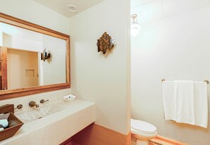 A bathroom with a large mirror, a sink with a wooden tray, a toilet, and a towel rack. - Hilton Grand Vacations Club Zihuatanejo (Zihuatanejo)