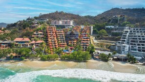 Un hôtel situé sur la côte, doté de nombreux balcons, d’une piscine et offrant une vue sur la plage.