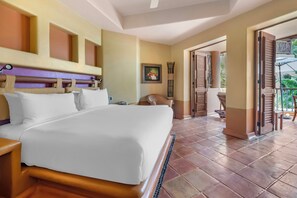 A hotel room with a large bed, a bedside table, a nightstand, a wall-mounted lamp, a framed picture, a tall floor lamp, and an open door leading to a balcony with outdoor furniture. - Hilton Grand Vacations Club Zihuatanejo (Zihuatanejo)