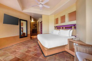 Habitación de hotel con una cama, una mesita de noche con teléfono, un espejo y un ventilador de techo.