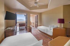 Une chambre d’hôtel avec deux lits, un bureau, une chaise, une télévision et un balcon avec vue.