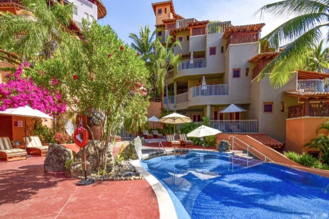 Un espace piscine d’hôtel avec une piscine à l’eau cristalline, des chaises longues et des parasols.