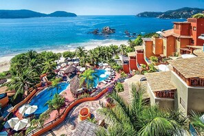 Een resort met zwembad, strand en uitzicht op zee.