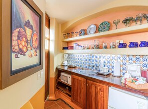 Una cocina con microondas, cafetera y varios utensilios de cocina en estantes.