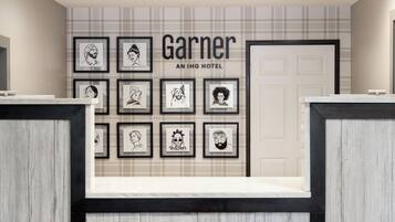 A hotel reception area with framed artwork on the wall and a reception desk.