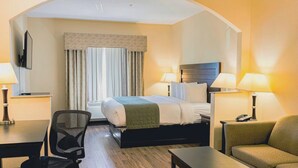 A hotel room with a bed, two bedside lamps, a desk, a chair, and a sofa. - Baymont by Wyndham Tyler (Tyler)