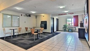 A hotel lobby with a vending area, a microwave, and a seating area with chairs and tables.
