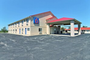 Un motel avec un toit rouge, une station-service et un parking.
