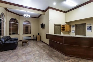 A lobby with a reception desk, a leather sofa, a small table, and a chandelier. - Super 8 by Wyndham Hurricane Zion National Park (Hurricane)