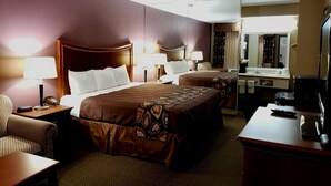A hotel room with two beds, a desk, a chair, a TV, and a bathroom mirror.