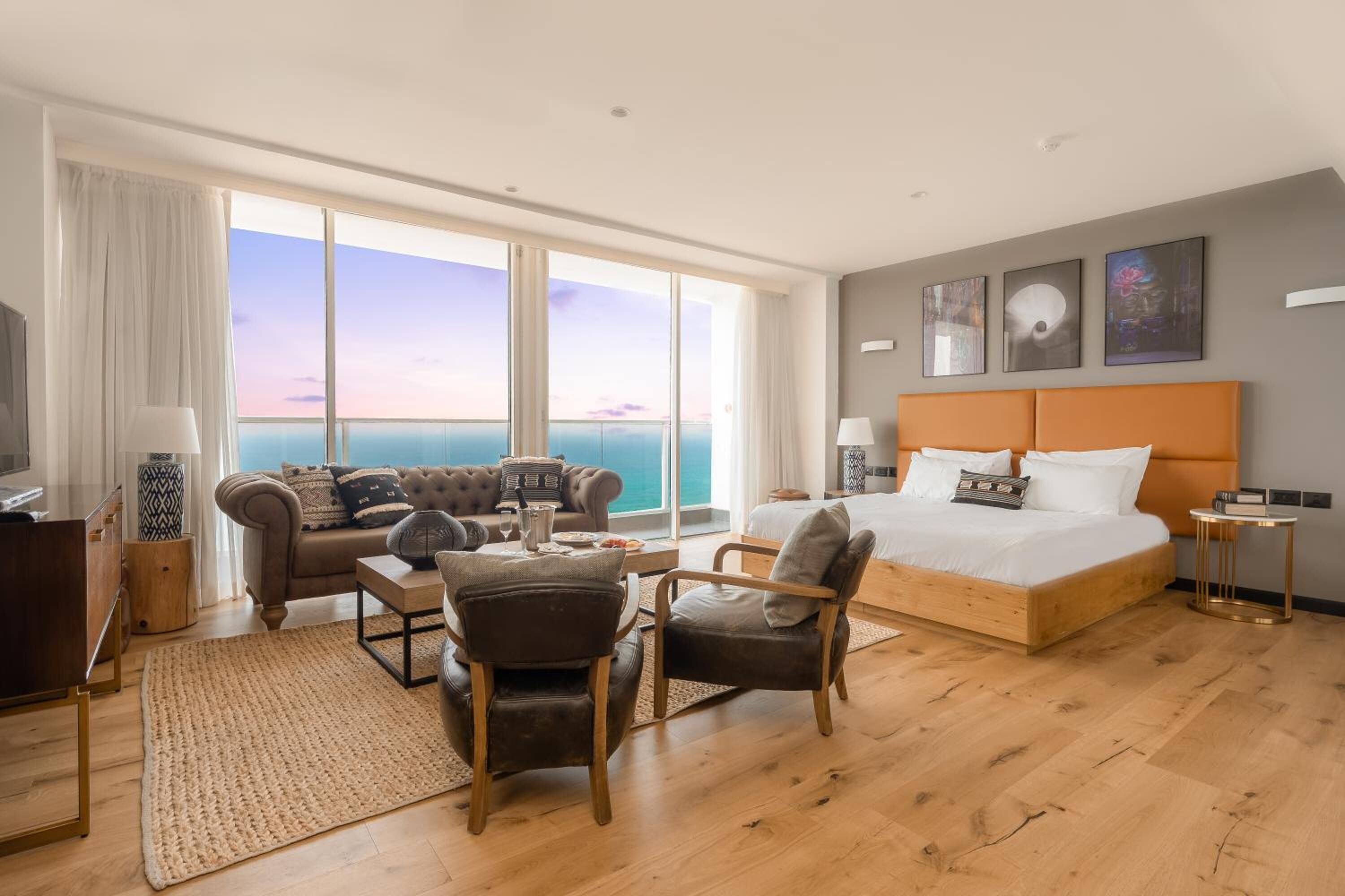 Una habitación de hotel moderna con una cama grande, un sofá, una mesa de centro y una televisión.