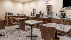 Un área de desayuno con mesas, sillas, una máquina de café, un microondas y un letrero para un restaurante de desayunos.