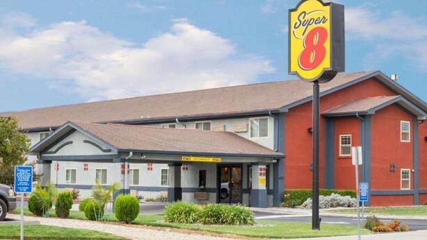 Un motel Super 8 con un edificio de dos pisos, un vestíbulo techado y un estacionamiento.