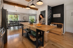 Une cuisine moderne avec une table en bois, un banc et un mur recouvert d’un tableau noir.