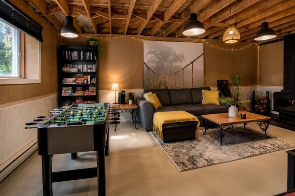 A cozy living room with a foosball table, a sofa, a coffee table, and a fireplace.