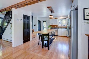 A spacious kitchen with wooden flooring, a central island, and a staircase leading to another level.