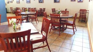 Ein Restaurantinneres mit Holztischen und -stühlen, Fliesenboden und an den Wänden befestigten Bildern.