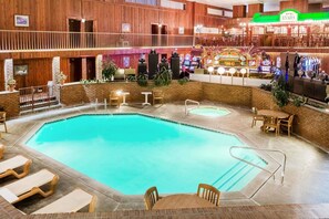 A pool area with lounge chairs, a hot tub, and a bar with slot machines.